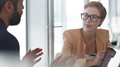 Man and woman dressed in business attire sitting and conversing.