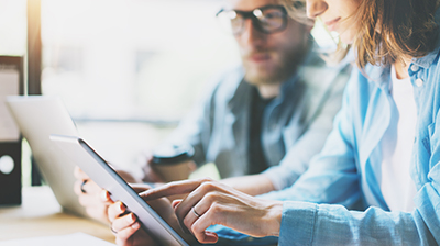Man and woman working on laptop and tablet