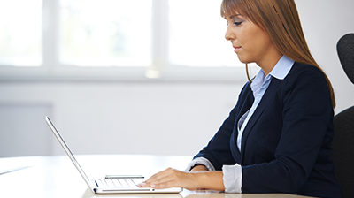 Woman in business attire working at a laptop
