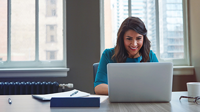 A woman smiling while using a laptop