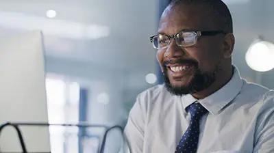 A business man smiling at his computer 